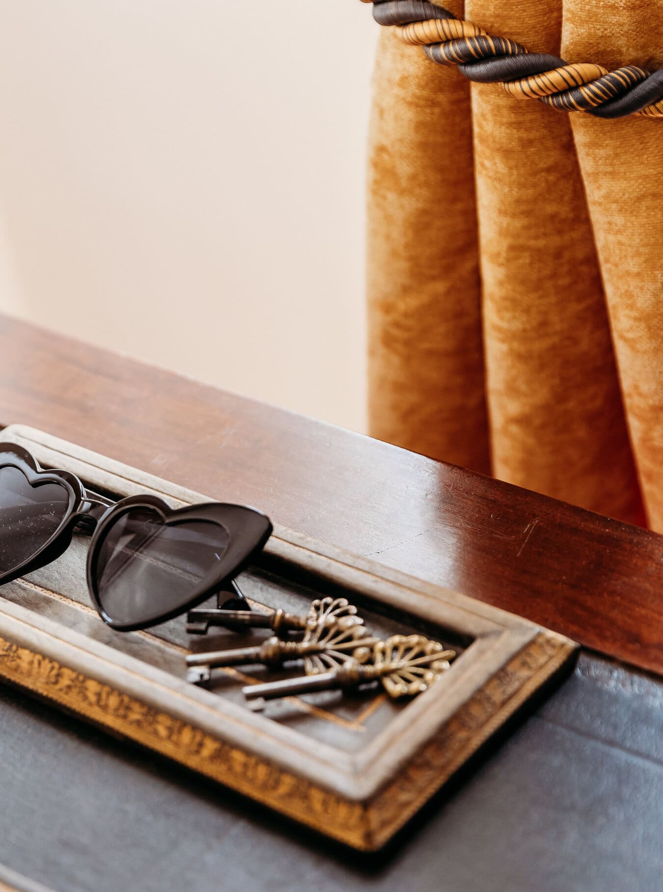 Heart-shaped sunglasses and antique keys on a vintage wooden tray. Chic bridal shower details with a Provence touch